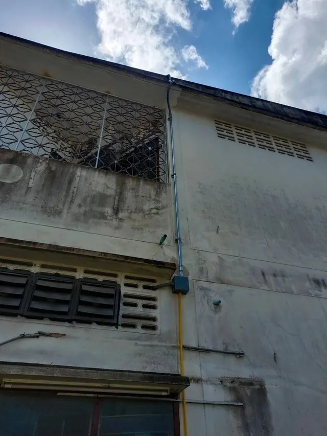 ท่อร้อยสายไฟโลหะเดินจากขอบหลังคาลงตามผนังด้านนอกเข้ากล่องพักสาย