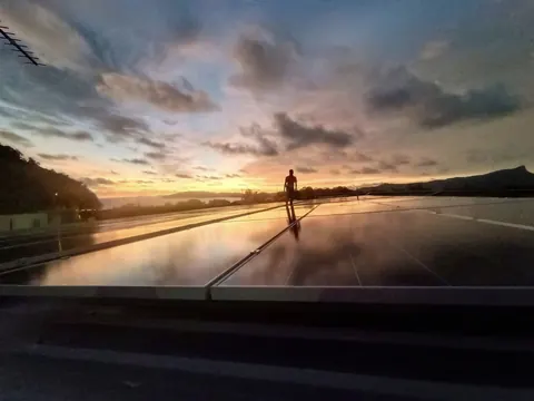 แผงโซล่าเซลล์บนดาดฟ้าสะท้อนแสงสีส้มในช่วงพระอาทิตย์ตกดิน