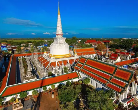 ภาพมุมสูงวัดที่มีเจดีย์และอาคารติดแผงโซล่าเซลล์บนหลังคา