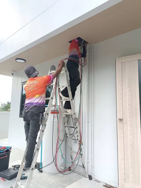 ช่างขึ้นบันไดติดตั้งอุปกรณ์ไฟฟ้าบริเวณผนังภายนอกอาคาร
