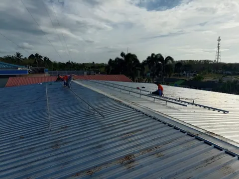 ช่างทำงานบนหลังคาโรงงานที่ติดตั้งรางยึดแผงเรียบร้อยแล้ว