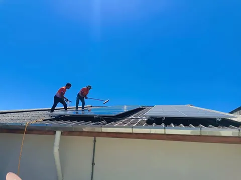 ช่างกำลังทำงานบนสันหลังคาอาคารใต้ท้องฟ้าสีคราม