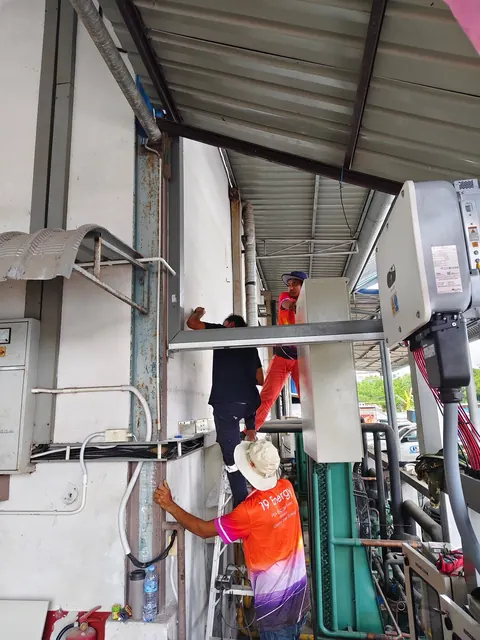 ช่างกำลังเดินท่อร้อยสายไฟตามผนังภายในอาคารโรงงาน