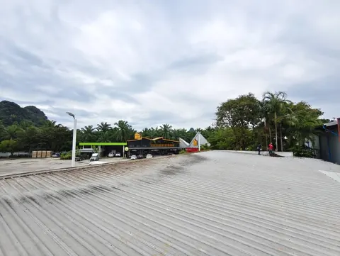 ดาดฟ้าเมทัลชีทกว้างที่เตรียมพื้นที่ติดตั้งแผง มีอาคารอยู่ด้านหลัง