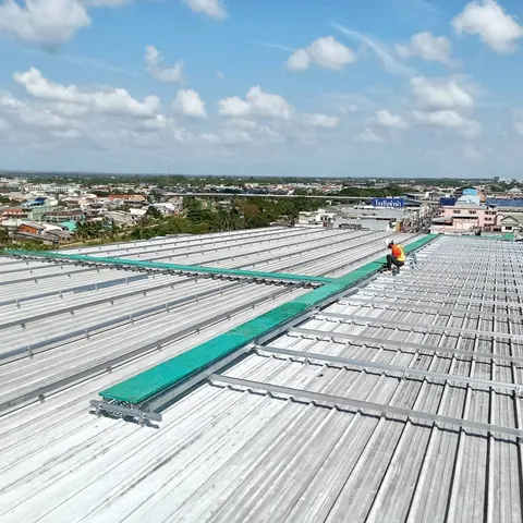 ภาพมุมสูงหลังคาโรงงานขนาดใหญ่ระหว่างติดตั้งโครงรางแผงโซล่าเซลล์