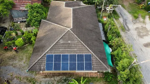 ภาพมุมสูงบ้านชั้นเดียวหลังคาจั่วติดแผงโซล่าเซลล์ ท่ามกลางสวนเขียวชอุ่ม