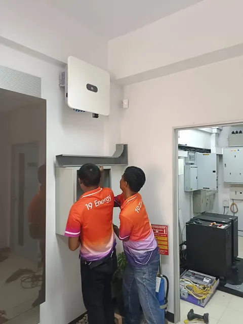 ช่างสองคนกำลังติดตั้งอินเวอร์เตอร์เข้ากับผนังภายในอาคาร