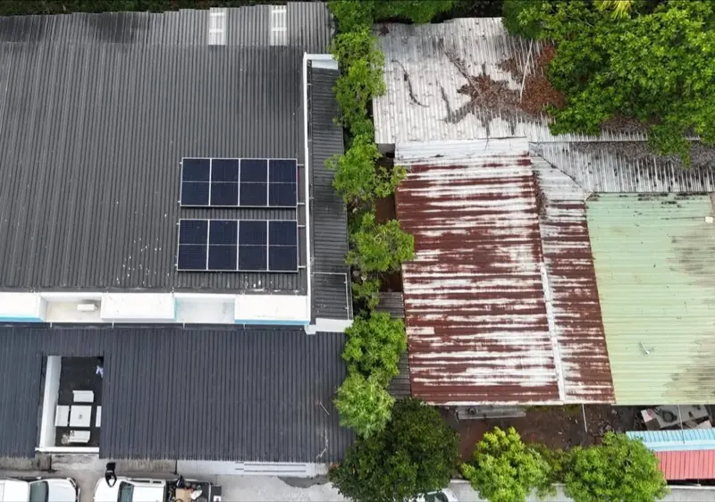 ภาพมุมสูงบ้านหลังคาจั่วที่ติดตั้งแผงโซล่าเซลล์ท่ามกลางสวนต้นไม้